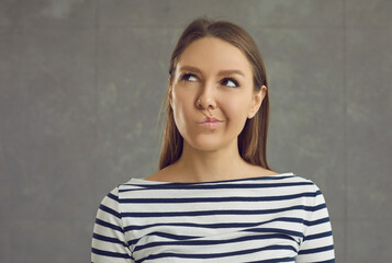 Studio headshot portrait of young caucasian doubtful woman looking up thinking or planning. Mindful...