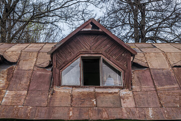 rusty roof and broken window in the attic of an abandoned wooden house