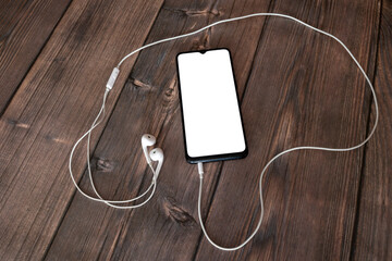 Smartphone and earphones on wooden background