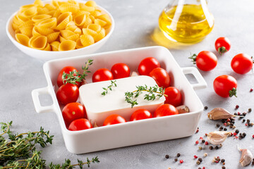 Step-by-step preparation and ingredients for oven-baked feta cheese with tomatoes and pasta, pepper garlic on a light background top view, mixing macaroni and cheese, trend recipe.