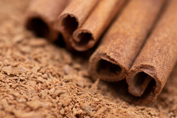 Close up view of cinnamon sticks on a pile of ground spice. Bark of cinnamon tree, that is used for cooking and backing.