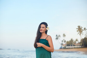 Fototapeta na wymiar Beauty portrait of female face with natural skin. Beautiful woman in green dress on the beach over sea and blue sky background. Skine care. Summer holidays, vacation, travel.