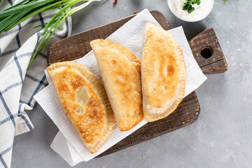 Cheburek - fried pie with meat and onions on a plate. Traditional dish of many turkic and mongolian peoples, pasties empanada. Top view. Copy space.