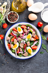 Salad with canned fish, eggs, spinach and tomato on a plate