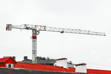 Tower crane against the gray sky builds a new city modern building on the construction site