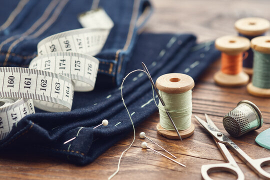 Shortening jeans. Measuring tape, scissors, spools of thread, thimble, including pins and chalk. Jeans cutting.