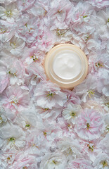 Fototapeta na wymiar Anti wrinkle face cosmetic cream or mask with herbal flowers. Skin and body care.Beautiful pink and white flowers background.Top view with copy space.