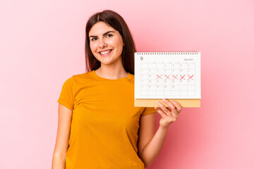 Young caucasian woman holding calendar isolated on pink background happy, smiling and cheerful.