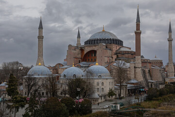Fototapeta na wymiar Hagia Sophia is located at the Sultanahmet square. It has high minarets and few large domes. The cathedral is made of red stone and is very large in size. Cloudy day in Istanbul.