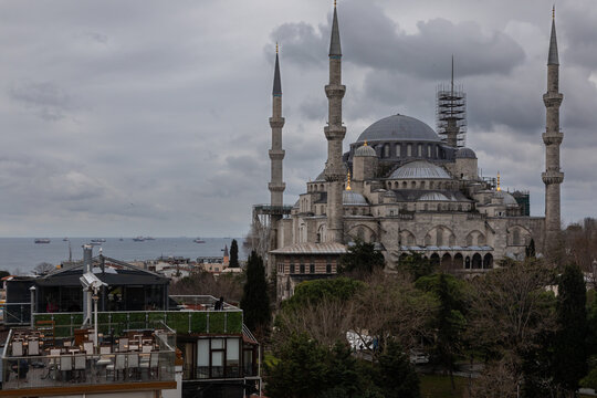 The Blue Mosque in Istanbul is located on Sultanahmet Square. It is made of gray stone, has high minarets. The photo was taken against the background of a sea shore on a cloudy day with dramatic sky
