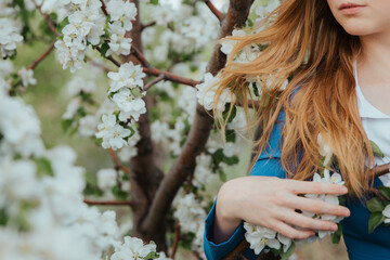 Detachment with nature. The blondes hair is intertwined with white apple blossoms. High quality photo