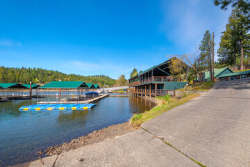 Fototapeta premium A waterfront cafe with patio overlooking a marina of boat slips and docks at Rockford Bay, in the mountains of rural Coeur d'Alene, Idaho, USA