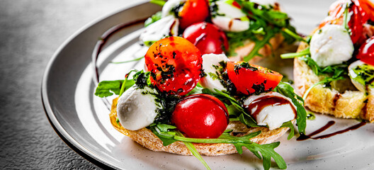 Italian bruschetta with roasted tomatoes, mozzarella cheese, balsamic vinegar and herbs on plate