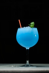 Glass of tasty summer cocktail on white marble and dark background. Cocktail Ocean Blue. Copy space for text.