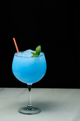 Glass of tasty summer cocktail on white marble and dark background. Cocktail Ocean Blue. Copy space for text.