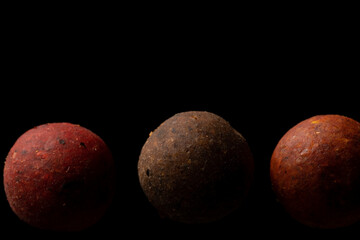 Protein balls for fishing carps of different colors on a black background. - obrazy, fototapety, plakaty