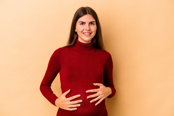 Obraz premium Young caucasian pregnant woman isolated on beige background happy, smiling and cheerful.
