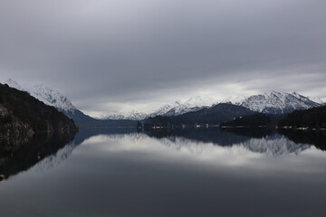 Crystal clear mountain lake in Patagonia, beautiful snowy mountain chain reflected in the calm water of the lake, with an astonishing mystical sky above, perfect place to meditate 