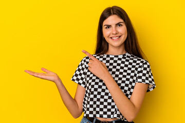 Young caucasian woman isolated on yellow background excited holding a copy space on palm.