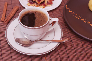 Still life - a hot cup of black coffee, homemade cookies with fruit on a bamboo mat