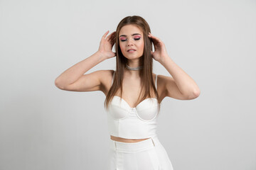 Obraz premium Stylish, well-groomed, young woman posing on a brown background. Lady touches her hair isolated on the background of an empty wall