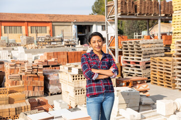 Smiling hispanic woman worker posing at building materials warehouse