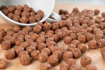 Crispy chocolate cereal flakes scattered on a wooden cutting kitchen board