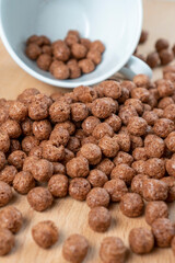 Chocolate cereal balls are scattered over the board with a white teacup