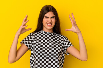 Young caucasian woman isolated on yellow background screaming with rage.