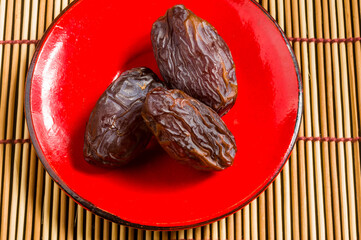 Big luxury dried date fruit in bowls on the bamboo mat, kurma ramadan kareem concept, close up.