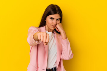 Young caucasian woman isolated on yellow background throwing a punch, anger, fighting due to an argument, boxing.