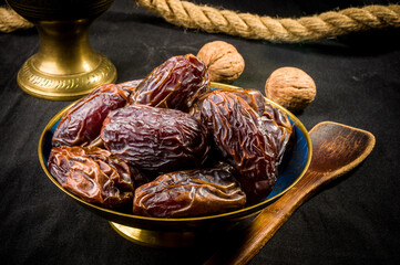 Big luxury dried date fruit in bowls on the dark surface, kurma ramadan kareem concept, close up.