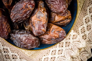 Big luxury dried date fruit in bowls on a linen napkin, kurma ramadan kareem concept, close up.