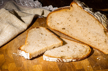 Still life - yeast-free buckwheat bread with sliced pieces, and a linen napkin on a wooden board, a wooden background, hard light, a photo in a low key.