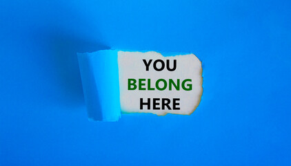 You belong here symbol. Concept words 'You belong here' appearing behind torn blue paper. Beautiful background. Business and you belong here, better inclusion concept. Copy space.