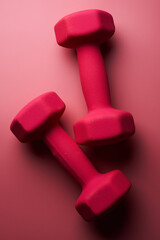 Two pink female dumbbells isolated on pink background close-up with copy space. Fitness concept, weight loss and sport activity