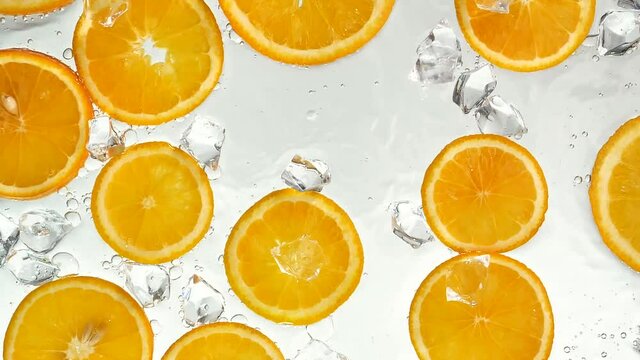 Oranges being doused with water, top view. Slow motion.