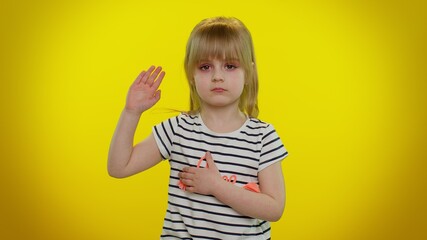 I swear to be honest. Sincere responsible cute kid child 5-6 years old raising hand to take oath, promising to be honest and to tell truth, keeping hand on chest on yellow wall. Children girl emotions - obrazy, fototapety, plakaty