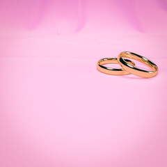 Wedding card design with two golden rings on pink background