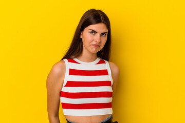 Young caucasian woman isolated on yellow background shrugs shoulders and open eyes confused.