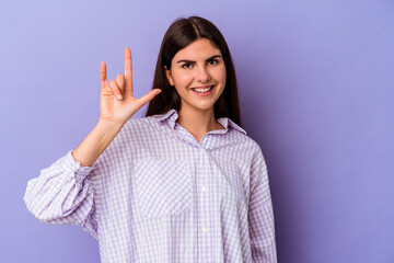 Young caucasian woman isolated on purple background showing rock gesture with fingers