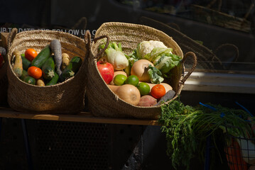 Baskets of vegetables at an outdoor market place in the spring. - obrazy, fototapety, plakaty