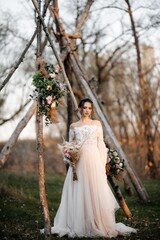 Obraz na płótnie Canvas A beautiful bride in a light dress poses. Boho style.