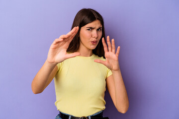 Young caucasian woman isolated on purple background rejecting someone showing a gesture of disgust.