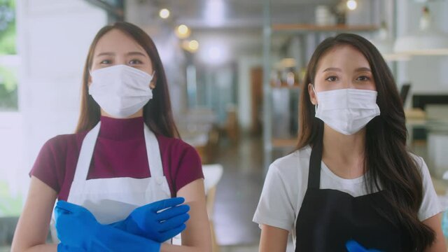 Portrait of a beautiful attractive asian female woman worker taking of face mask and rubber glove finishing clean up work process