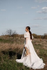 Fototapeta na wymiar A beautiful bride in a light dress poses. Boho style.