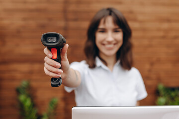 Seller smiling and holding barcode scanner in a hand.