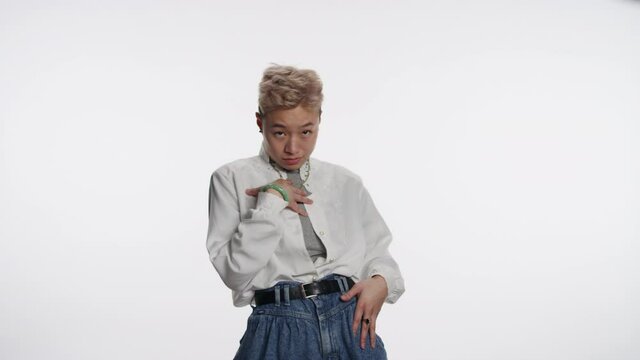 Young non-binary Asian person gestures who me?