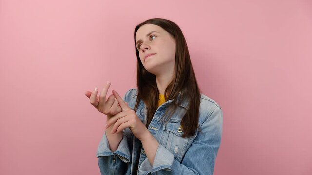 Thoughtful young brunette female bending fingers, counting to ten and looking with contemplation, calculation, wears denim jacket, posing isolated on pink background. People emotion lifestyle concept
