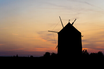 an old windmill silhouette at sunset, windmills of Tes at sunset